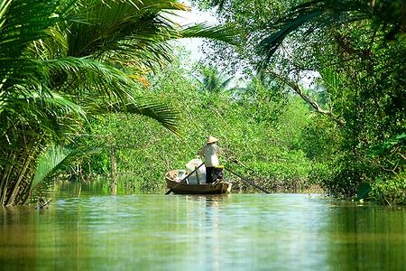 Uomo su barca nel verdeggiante delta del Mekong a Can Tho, Vietnam.