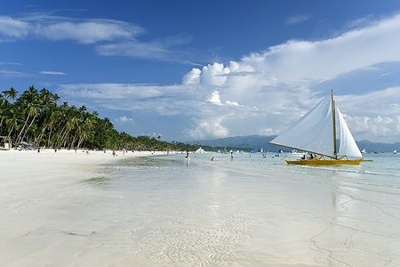 Barca paraw sulla spiaggia bianca di Boracay nelle Filippine sotto un cielo sereno.