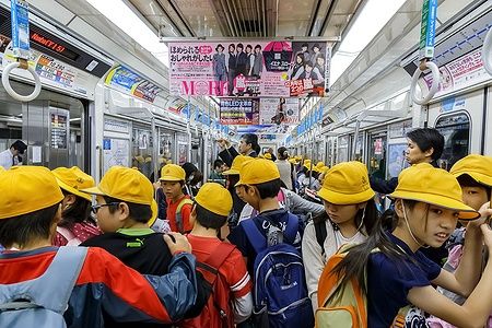 Studenti giapponesi con cappelli gialli su un treno della metropolitana a Osaka.