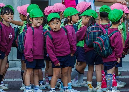 Bambini giapponesi in fila con uniformi colorate davanti allo zoo di Osaka.