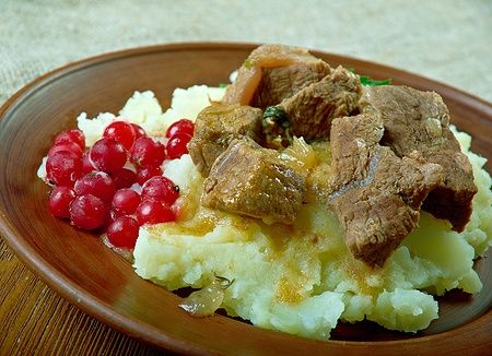 Bistecca di renna saltata con purè di patate e mirtilli rossi su piatto.
