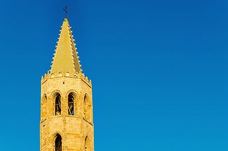 Campanile della Cattedrale di Santa Maria ad Alghero contro un cielo azzurro.