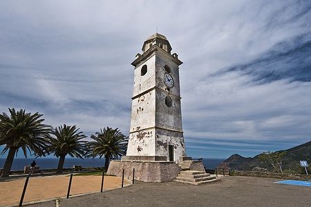 Campanile nel villaggio di Canari, Cap Corse, Francia, con cielo e palme.