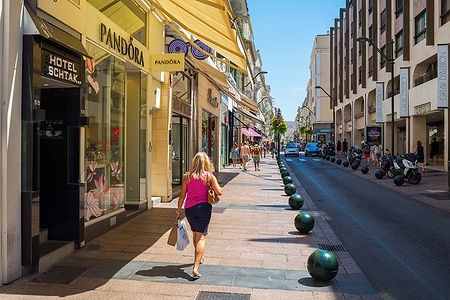 Rue d'Antibes a Cannes, donna cammina tra negozi di lusso.