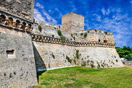Mura del Castello Svevo di Bari sotto un cielo blu.