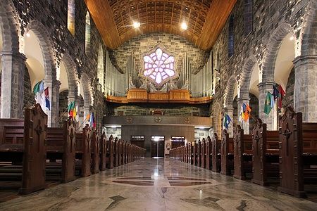 Interno della Cattedrale di Galway con archi in pietra e rosone centrale.