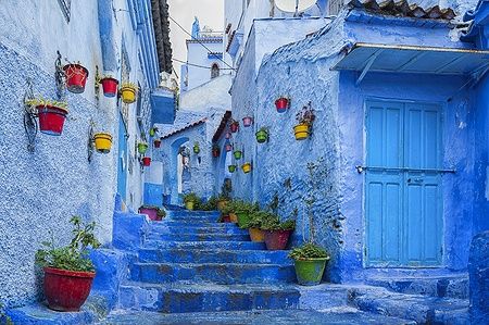 Strada blu di Chefchaouen con vasi colorati sulle pareti.