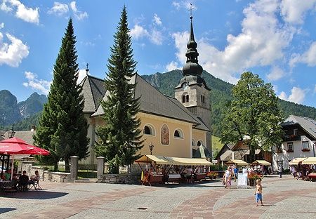 Chiesa centrale di Kranjska Gora con persone e montagne sullo sfondo.