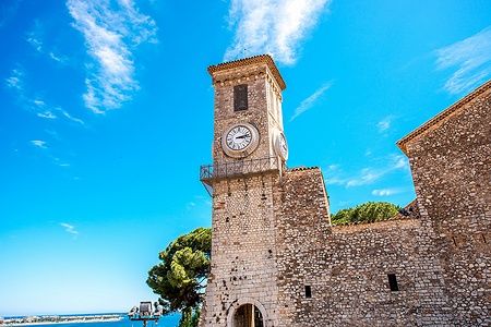 Chiesa di Notre-Dame de l'Espérance a Cannes con torre e cielo blu.