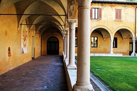 Chiostro rinascimentale del Museo di Santa Giulia a Brescia con arcate e prato verde.
