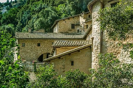 Eremo delle Carceri ad Assisi con edifici in pietra circondati dalla natura.