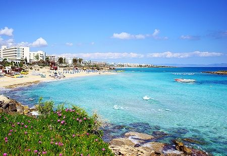 La baia di Fig Tree Bay a Cipro con acque azzurre e spiaggia affollata.