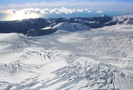 Vista del ghiacciaio Franz Josef in Nuova Zelanda, circondato da montagne sotto un cielo sereno.
