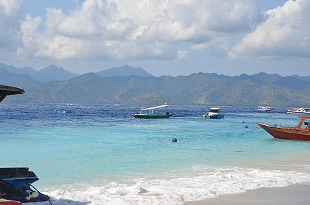 Costa dell'isola di Gili con acque cristalline e barche, Indonesia.