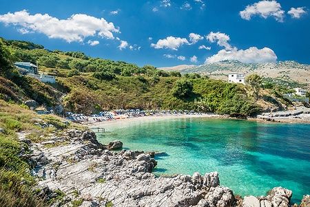 Spiaggia di Kassiopi a Corfù con ombrelloni e lettini.
