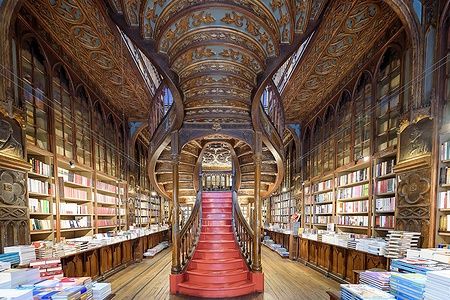 Interno della Livraria Lello a Porto con scala rossa e scaffali pieni di libri.