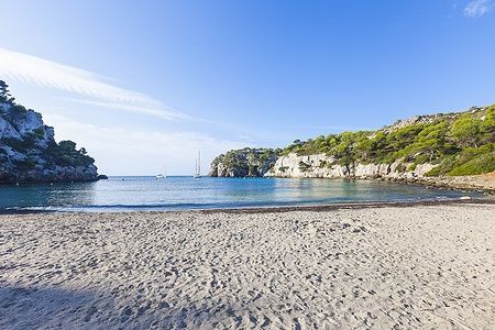 Spiaggia di Macarella a Minorca al mattino con acque calme e scogliere.