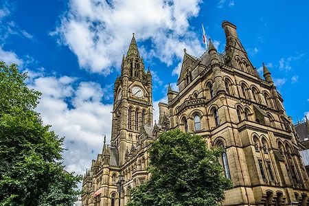 Il municipio di Manchester con la torre dell'orologio sotto un cielo blu.