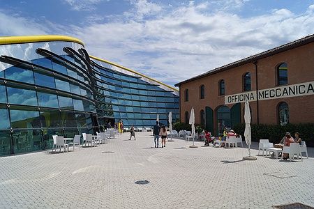 Esterno del Museo Enzo Ferrari a Modena con visitatori seduti all'aperto.