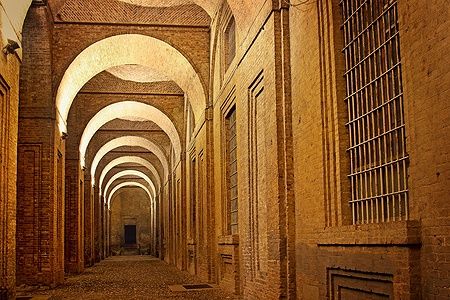 Galleria con archi a volta illuminati di notte al Palazzo della Pilotta a Parma.