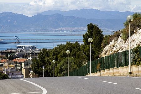 Vista del porto di Cagliari da Monte Urpinu con mare e montagne.