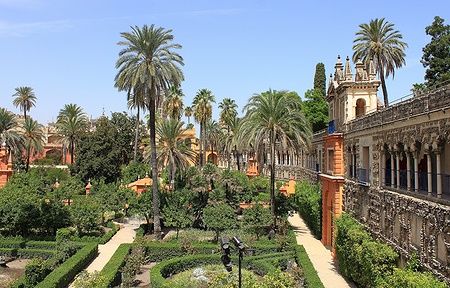 Giardini del Real Alcázar a Siviglia con palme e architettura moresca.