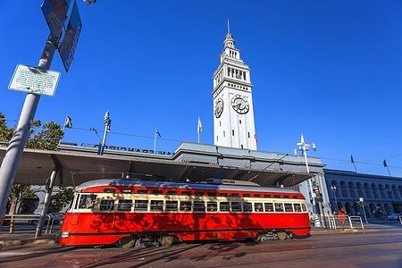 Tram rosso davanti al San Francisco Ferry Building con torre dell'orologio.
