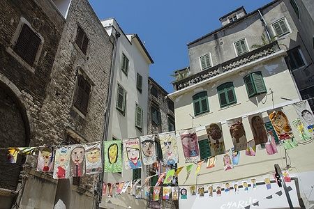 Facciate di edifici storici a Sibenik, Croazia, con disegni appesi.