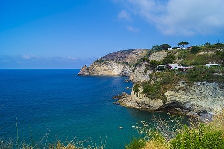 Vista di Sorgeto beach a Ischia con scogliere e mare blu.