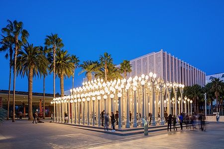 Lampioni illuminati dell'installazione 'Urban Light' al LACMA al crepuscolo con persone intorno.