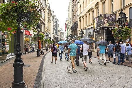 Turisti con ombrelli passeggiano su Vaci street a Budapest.