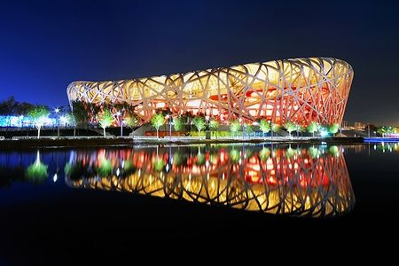 Il Bird's Nest illuminato si riflette in un lago notturno a Pechino.