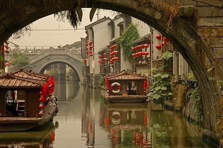 Vista su un canale a Suzhou con barche e lanterne rosse.