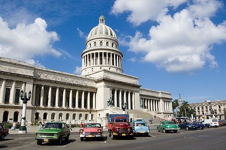 Il Capitolio di Havana con auto d'epoca parcheggiate davanti, sotto un cielo azzurro.
