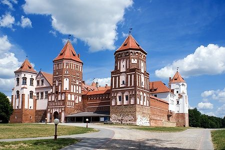 Il Castello di Mir in Bielorussia con torri in mattoni rossi sotto un cielo azzurro.