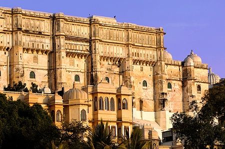 Il City Palace di Udaipur con architettura in pietra rossa contro un cielo limpido.