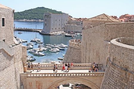 Mura della città di Dubrovnik con porto e barche sullo sfondo.