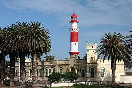 Il faro di Swakopmund e l'edificio storico con palme sullo sfondo.