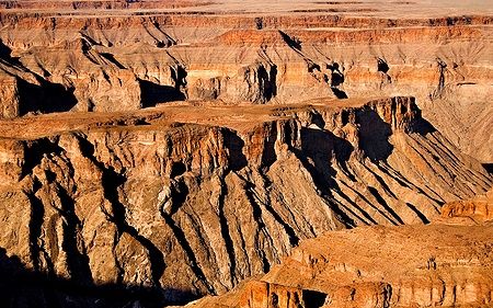 Fish River Canyon al crepuscolo, Namibia, con strati di roccia illuminati dalla luce del tramonto.