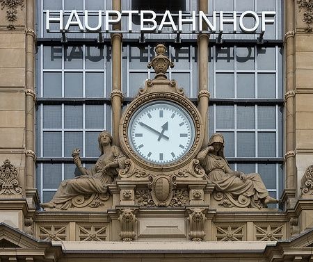 Facciata del Hauptbahnhof di Francoforte con orologio e sculture classiche.