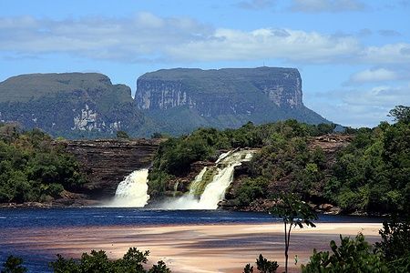 Cascate e laguna a Canaima sotto un cielo azzurro.