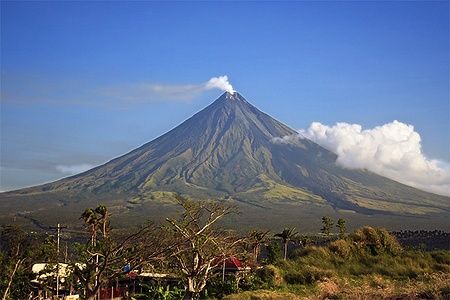 Il vulcano Mayon si erge con la sua forma perfetta e una nube di fumo.