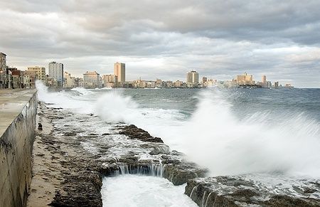 Onde infrangono il Malecon dell'Avana con la città sullo sfondo.