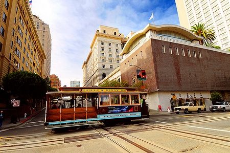 Cable Car a San Francisco attraversa il centro città con edifici storici sullo sfondo.