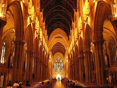 Interno della St Mary's Cathedral a Sydney con archi gotici e persone sedute.