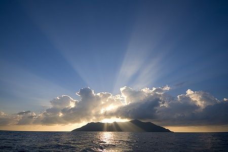 Tramonto su Silhouette Island alle Seychelles con nuvole illuminate dal sole.
