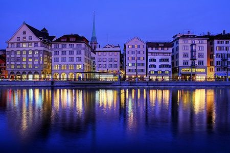 Skyline di Zurigo di notte con riflessi sul fiume Limmat.