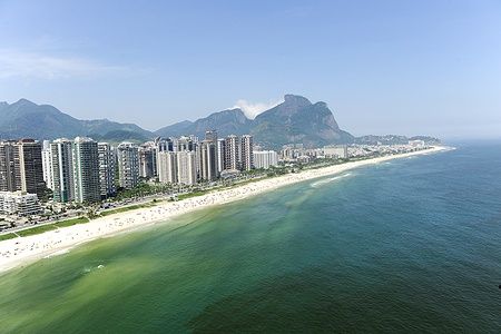 Spiaggia di Barra da Tijuca a Rio de Janeiro, con grattacieli e montagne sullo sfondo.