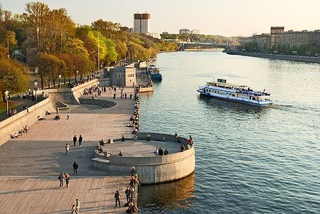 Lungofiume della Moscova nel parco Gorky con persone e un battello.