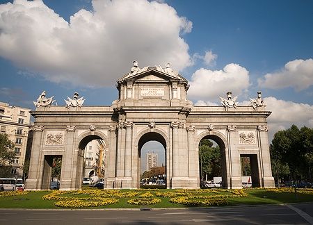 Puerta de Alcalá nella Piazza dell'Indipendenza a Madrid sotto un cielo nuvoloso.